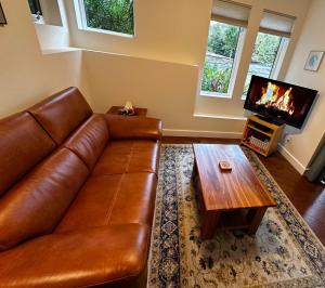 een woonkamer met een bruine leren bank en een salontafel bij Liahona Guest House in Ucluelet