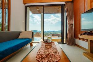 a living room with a blue couch and a large window at Andakiri Private Pool Villa Sea View in Ao Nang Beach