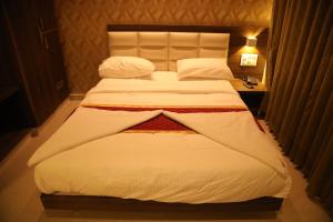 a bedroom with a large bed with white sheets and pillows at Royal Indraprastha The Hotel in Bengaluru