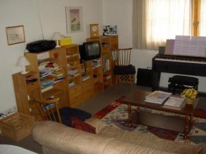 uma sala de estar com um sofá e um piano em Ferienwohnung Munt plan immez 140B em Ftan