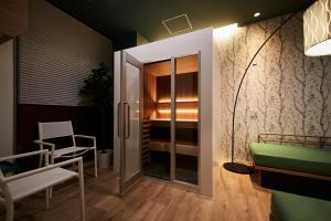 une chambre avec une porte coulissante en verre et une chaise dans l'établissement MONday Apart Premium KYOTO Station, à Kyoto