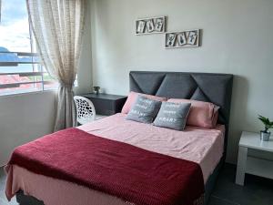 Un dormitorio con una cama con sábanas rosas y moradas y una ventana. en Ins2 Langkawi Apartment Kuah en Kuah