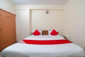 een slaapkamer met een groot wit bed met rode kussens bij Flagship Hotel Arsh in Bhowāli