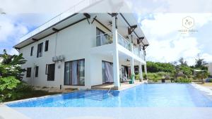 a villa with a swimming pool in front of a house at Hanamitsu Hotel & Spa in Garapan