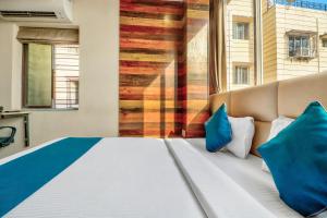 a bedroom with a large bed with blue pillows at Super Hotel O Park Circus Near Birla Mandir in Kolkata