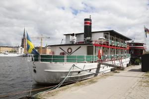 a boat is docked next to a building on the water at Den Röda Båten in Stockholm