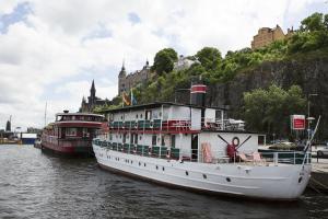 two boats are docked in the water near a city at Den Röda Båten in Stockholm