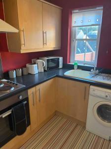 a kitchen with a sink and a microwave at Centralized Complete 3 BR Flat at Newcastle-Under-Lyme with a View-Free Parking in Newcastle under Lyme