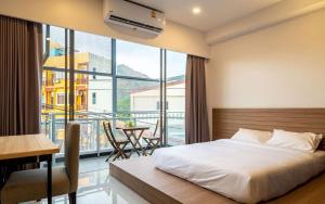 1 dormitorio con 1 cama y balcón con mesa en Kata Poshtel Phuket, en Kata Beach