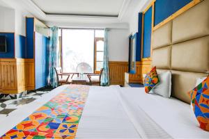 een slaapkamer met een groot bed en een raam bij FabHotel Rosewood Inn I in Dharamshala