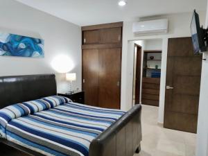 a bedroom with a bed with a blue and white striped blanket at Brujas Tower Beach Resort in Mazatlán