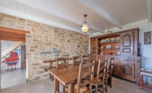 una sala da pranzo con tavolo in legno e parete in pietra di Menhir a Hôpital-Camfrout