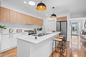 an open kitchen with white countertops and wooden cabinets at Aerial Beach House - Beach & Golf in Torquay
