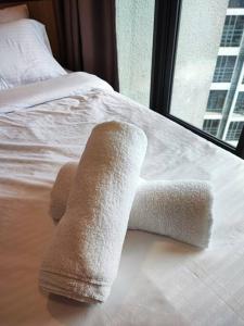 einen Haufen Handtücher auf einem Bett mit Fenster in der Unterkunft ekocheras duplex suites with balcony, drinking water, Karaoke K in Kuala Lumpur