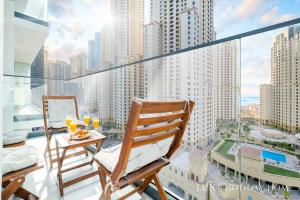 einen Balkon mit 2 Stühlen und einem Tisch mit Getränken in der Unterkunft LUX Contemporary Suite with Full Marina View 6 in Dubai