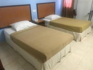 two beds in a hotel room with two beds at Lily Budget Hotel in Jertih