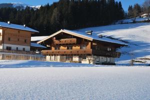 un gran edificio de madera con nieve en el suelo en Gästehaus Einödberg, en Mittersill