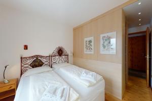1 dormitorio con 1 cama grande con sábanas blancas en Apartment Sur Puoz 2A en Samedan