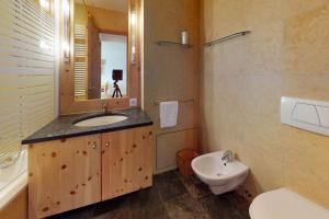 y baño con lavabo, aseo y espejo. en Apartment Sur Puoz 2A en Samedan