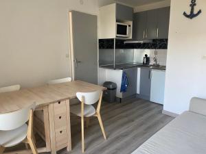 kuchnia z drewnianym stołem i krzesłami w pokoju w obiekcie Appartement entier en résidence, fonctionnel et confortable w mieście Cabourg