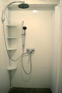 a shower with a hose in a white tiled bathroom at Ferienwohnung Ela 1 in Andernach