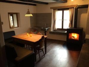 uma sala de estar com uma mesa de madeira e um fogão a lenha em Sunny, rustical 5 room cottage in Valposchiavo em Poschiavo