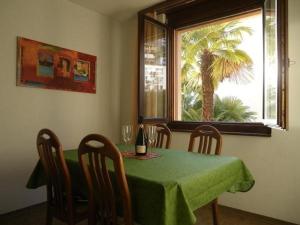 uma sala de jantar com uma mesa e uma janela com uma palmeira em Appartementhaus Onyx - zentrale, ruhige Lage - neu renoviert - mit Hallenbad - 600 Schritte vom Bahnhof em Muralto
