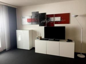 uma sala de estar com uma televisão num armário branco em Gemütliche Ferienwohnung im Disentiserhof mit Traumblick übers Rheintal em Disentis