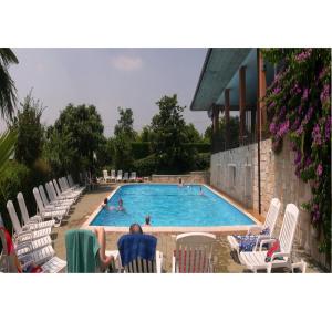 a swimming pool with chairs and people in the water at Residence Miralago Rooms & Apartments in Manerba del Garda