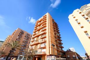 een hoog gebouw in een stad met palmbomen bij Sea & Mountain, front line, 1 min to beach by 10ToSea in Fuengirola
