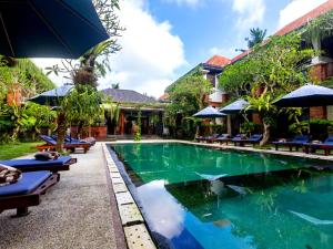 una piscina en un complejo con sillas y sombrillas en Awatara Boutique Resort Ubud, en Ubud