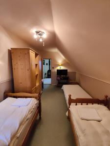 a attic room with two beds and a tv at Szendergő - Apartman Hajós pincefalu in Hajós