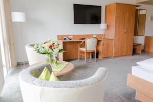 une chambre d'hôtel avec un canapé et une table avec des fleurs dans l'établissement Gästehaus Wilgersdorf GmbH, à Wilnsdorf