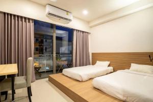 1 dormitorio con 2 camas, escritorio y ventana en Kata Poshtel Phuket, en Kata Beach
