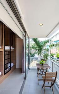 Habitación con mesa, sillas y balcón. en Kata Poshtel Phuket, en Kata Beach