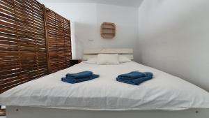 2 asciugamani blu sono seduti su un letto bianco di Beautiful Studio With Patio Carrapateira a Carrapateira