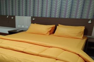 - un lit avec des draps et des oreillers jaunes dans l'établissement Smart Dream Aeropolis AR2, à Teko