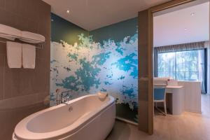 a bathroom with a tub and a painting on the wall at Centra by Centara Maris Resort Jomtien - SHA Extra Plus in Jomtien Beach