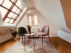 Zimmer mit 2 Stühlen, einem Tisch und einem Fenster in der Unterkunft Jugendstil-Altbauwohnung mit Dachterrasse direkt an der Karlsaue in Kassel