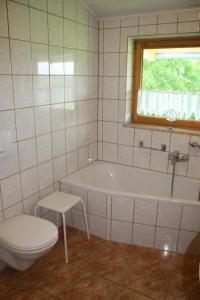 uma casa de banho com uma banheira, um WC e uma janela. em Große Wohnung in Fürsteneck mit Grill und Terrasse em Fürsteneck
