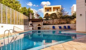 una piscina con sedie blu accanto a un edificio di Wonderful Villa in Chania with Private Pool, Panoramic Sea Views & Spacious Interiors ad Agios Onoufrios