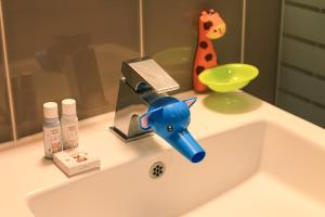 a bathroom sink with a blue faucet and a giraffe toy at Kensington Resort Seorak Beach in Sokcho