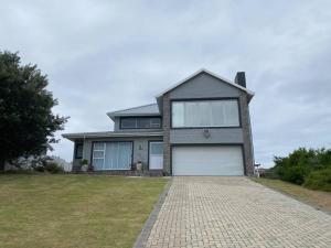 a large house with a garage on a brick driveway at Grys Patrys - 4 Beds Beach Home in Jeffreys Bay