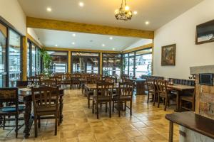 un restaurante con mesas y sillas de madera y ventanas en Hotel Center Bohinjsko Jezero en Bohinj