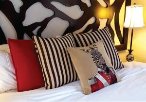 łóżko z dwoma poduszkami z zebrą w obiekcie Waterside Cottages w mieście Gaborone