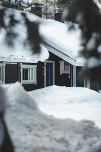 una casa con una puerta azul cubierta de nieve en Economy Aarakka en Levi