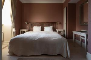 a bedroom with a white bed with two tables and a window at Grand Hotel Marstrand in Marstrand