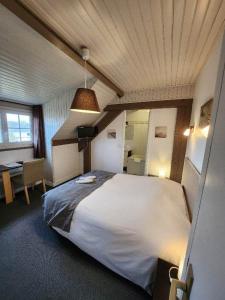 a bedroom with a large white bed and a desk at Logis Auberge des Aulnettes in Houlgate