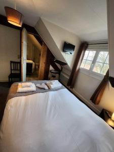 a bedroom with a large bed with towels on it at Logis Auberge des Aulnettes in Houlgate