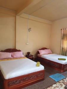 a bedroom with two beds with pink pillows at Phanyro Motel in Senmonorom